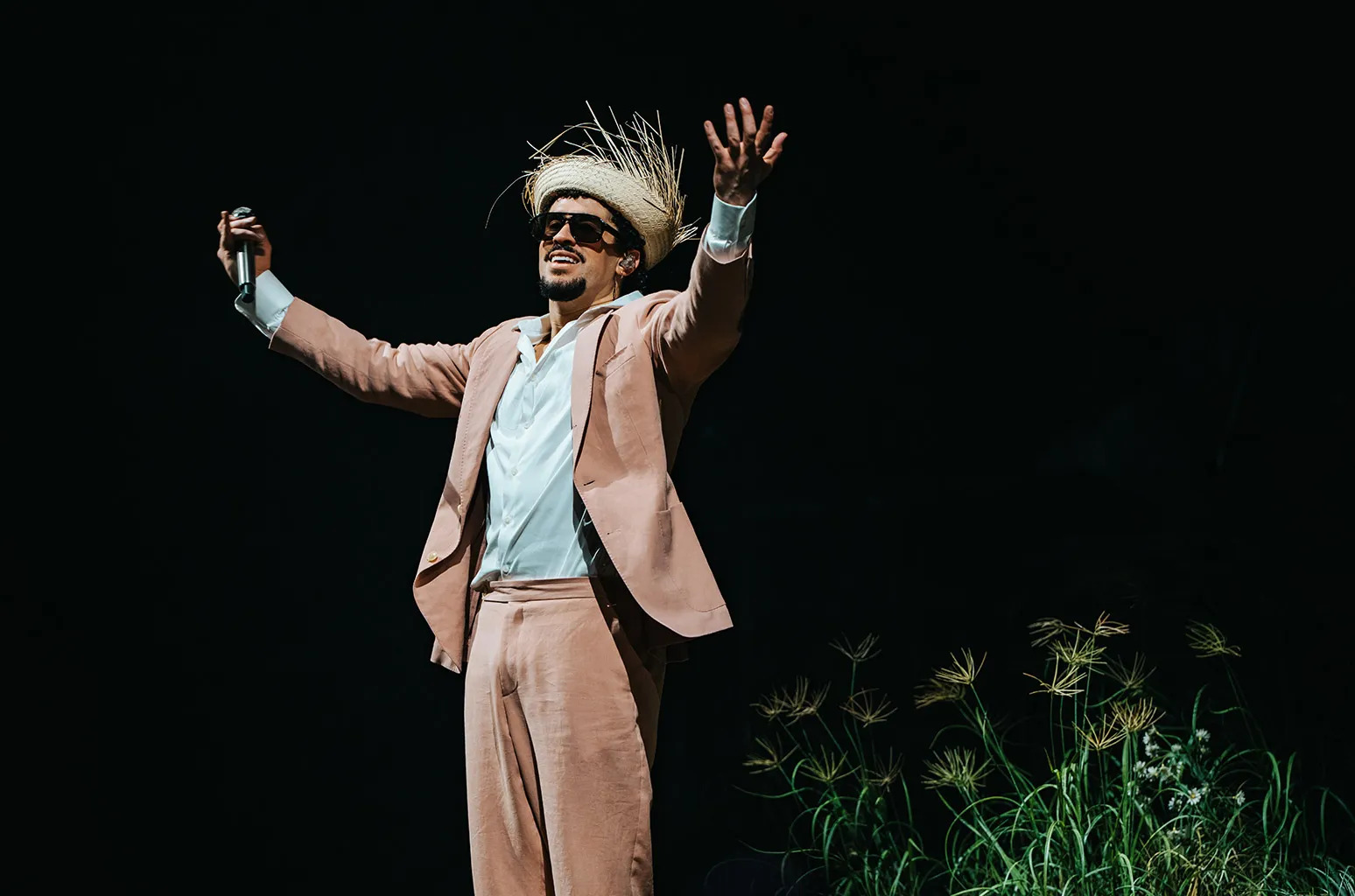 Bad Bunny on stage in pink suit with straw hat