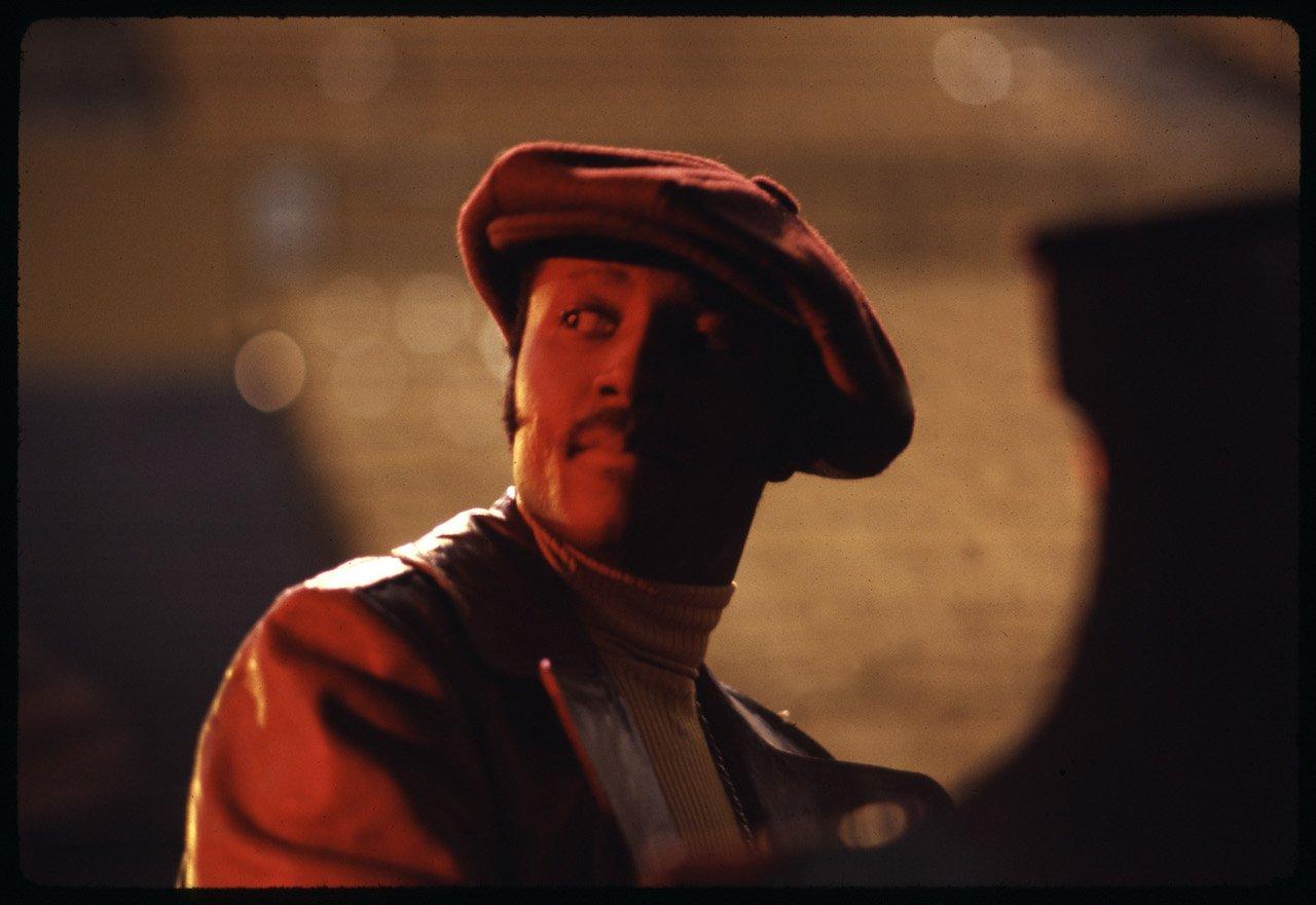 Portrait of Donny Hathaway at the piano wearing hat with red lighting