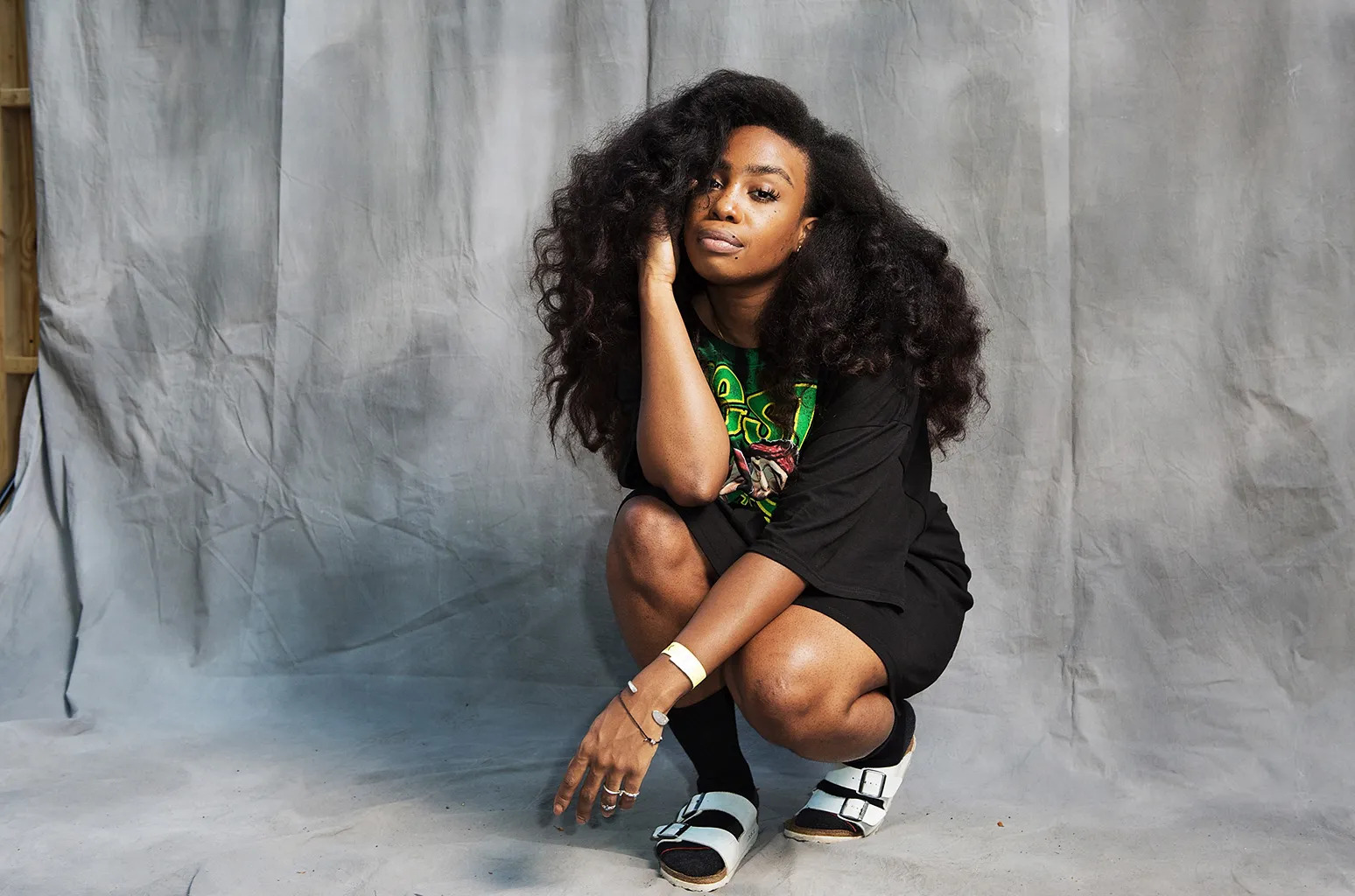 SZA posing for a portrait with a grey background