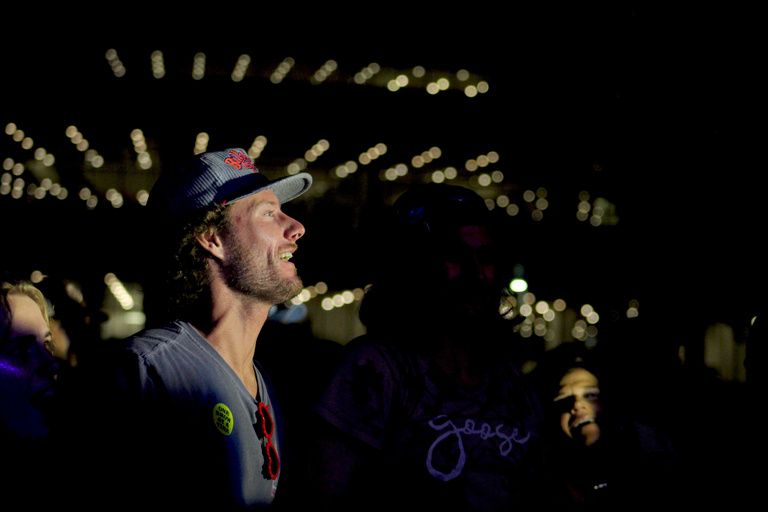 fan enjoying the concert, only light showing his face the rest is blacked out