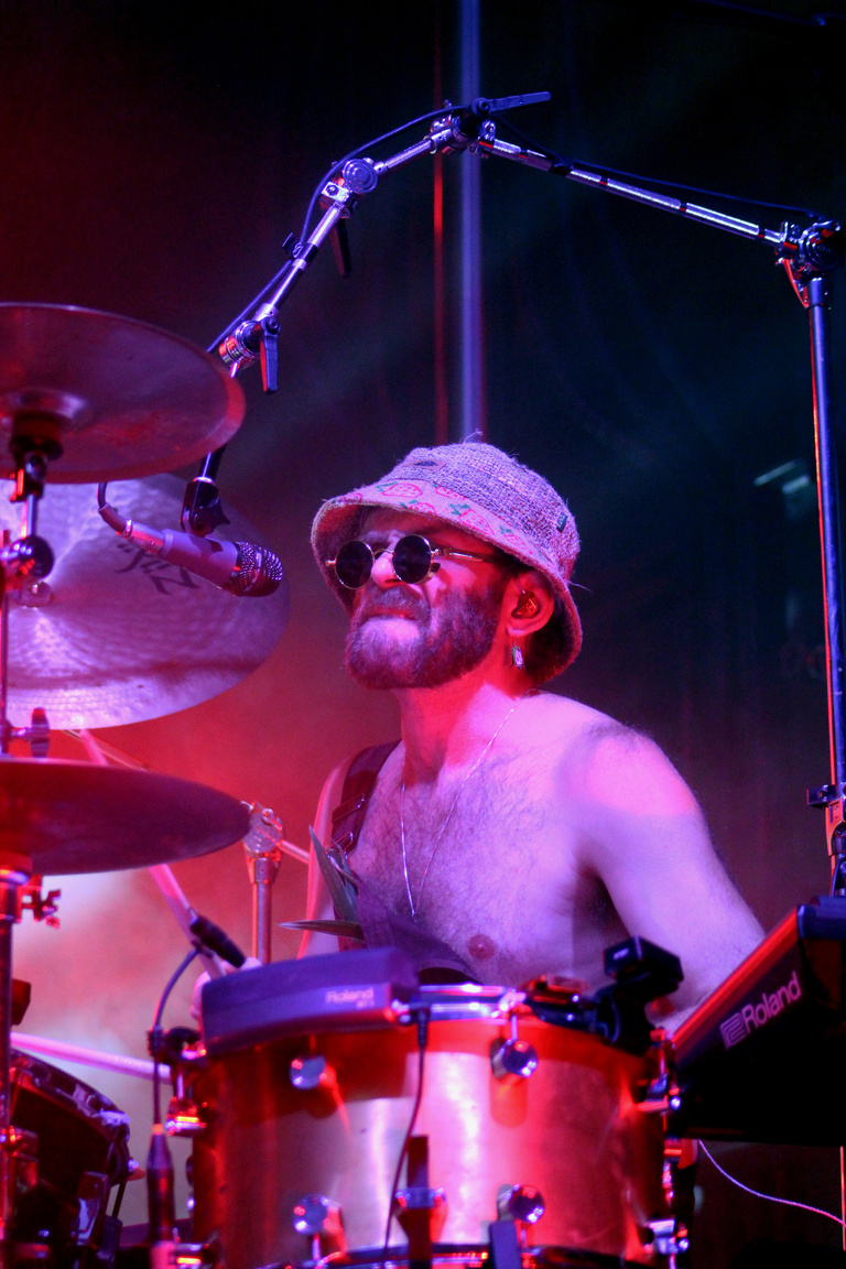 Drummer of Goose instensely playing the drums with red and purple lighting