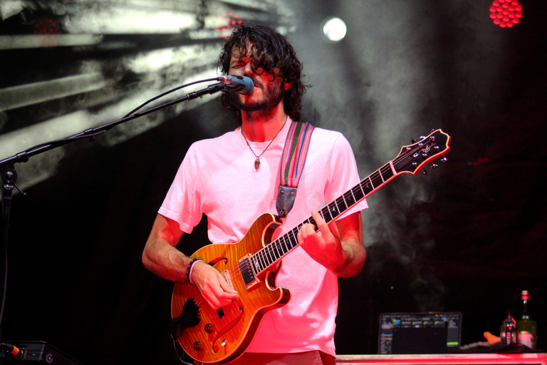 Lead singer and guitarist of Goose on stage with red lighting