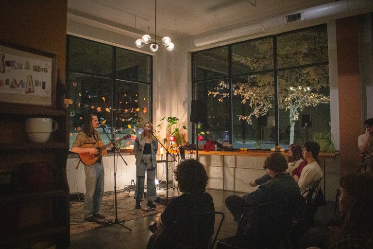 Side angle shot of the event. Front row of audience listening to music while the performance is happening. 