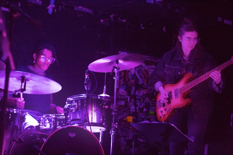Drummer and bass player on stage with purple low lighting
