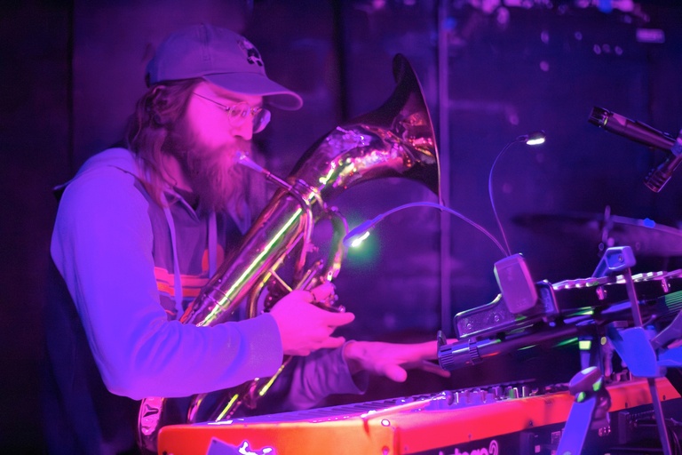 Band member playing keys and baritone at the same time in purple lighting