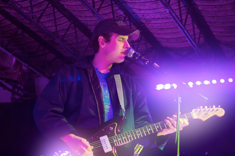 Close up of Dan English in purple lighting on stage while playing guitar