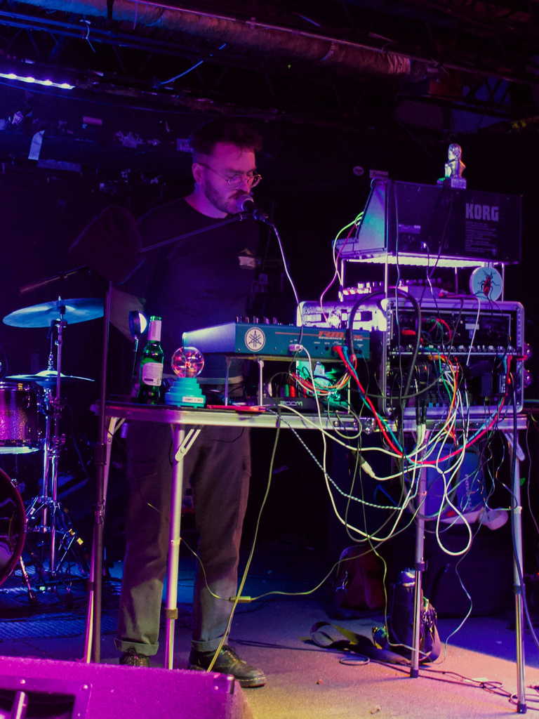 Blue low lighting picture of Birdlabs on stage with sound board