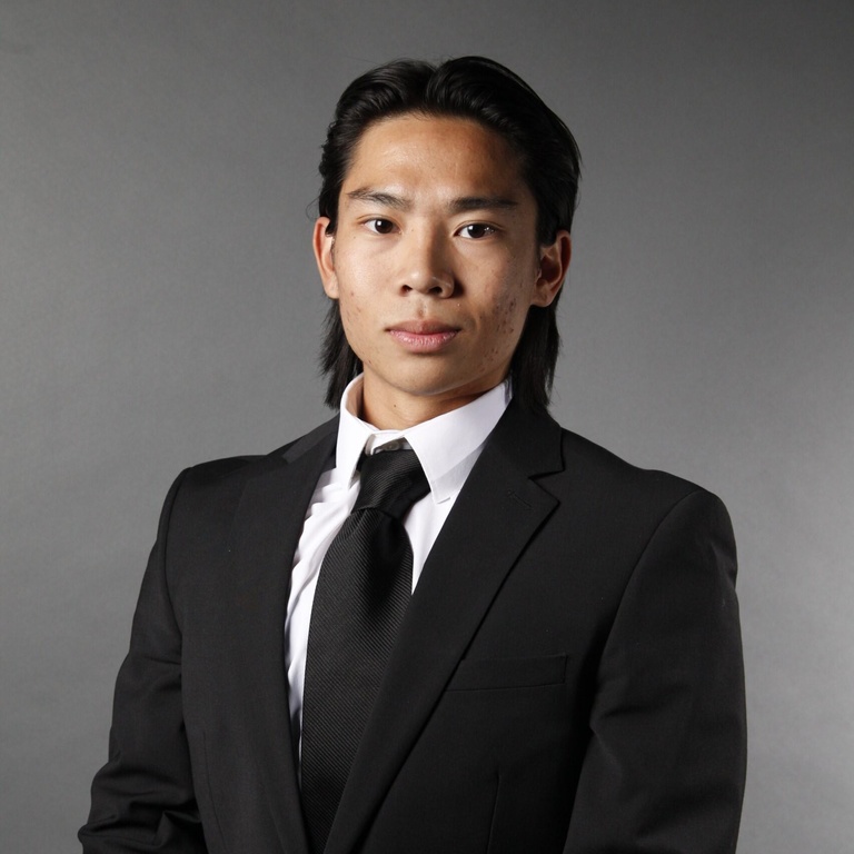 grey background, black suit and tie, white shirt